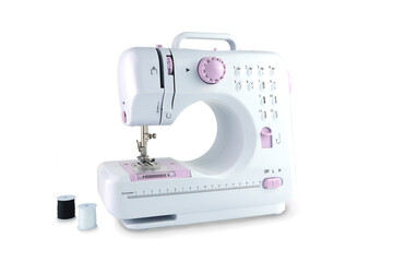 multifunction modern cute white and pink color sewing machine is on the white table with two sewing threads with background of white wall in the room for tailoring garments