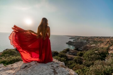 Woman sunset sea red dress, back view a happy beautiful sensual woman in a red long dress posing on...