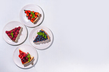 

Summer cafe baking menu background, sweet cheesecake portion slices with various toppings, jam and berry fruits - strawberry, blueberry, raspberry, cherry 