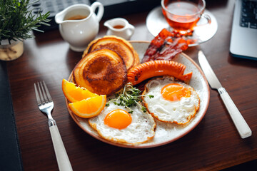 Fototapeta na wymiar Breakfast pancakes, fried eggs, bacon, sausage and coffee.
