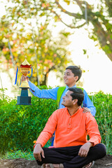 Cute indian farmer child in school uniform with his father at agriculture field