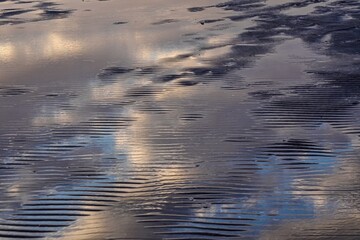 Colorful reflection of the sky on the water on a sandy beach