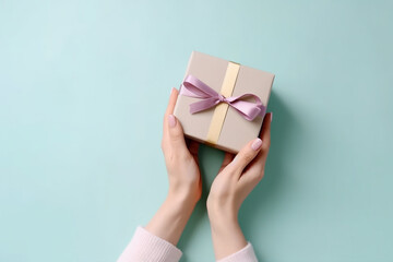 Female hands holding small giftbox in pastel colors over the light blue background, top view. Generative AI