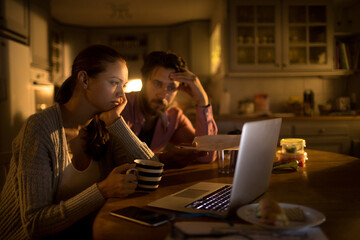 Worried young couple going over their home finances and bills late at night