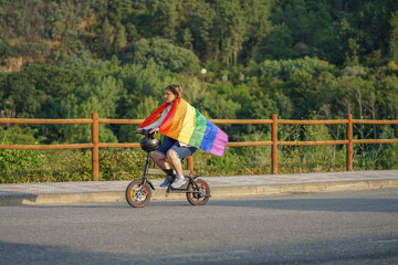 middle aged woman holding lgtbiq flag while riding electric bike