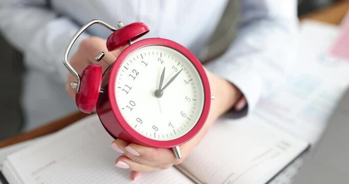 Business woman setting time on alarm clock in office closeup. Time management concept