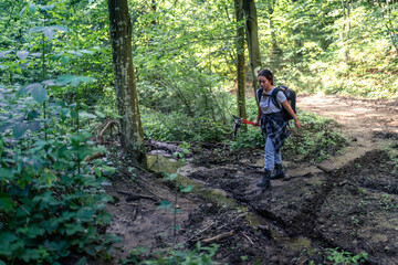 Fototapeta premium a young mountaineer walks through the forest and crosses a shallow stream