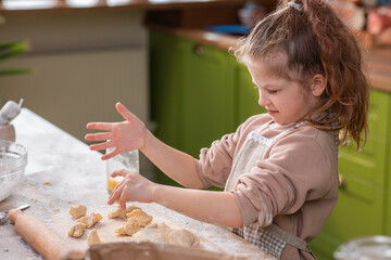 Very excited cute pretty girl blowing the flour while preparing the dessert for all family members at the modern kitchen island