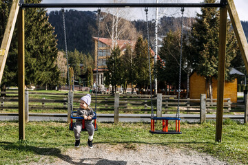 one child on swing at a playground on spring sunny day.