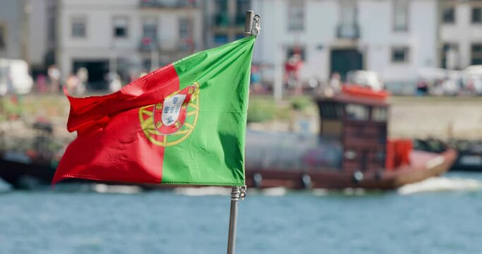 Portuguese national flag on mast of a traditional boat on Douro river in Porto
