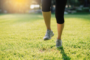 Embrace the concept of wellness living. Witness the close-up of a female jogger's legs and shoes as she runs during sunset in a public park.