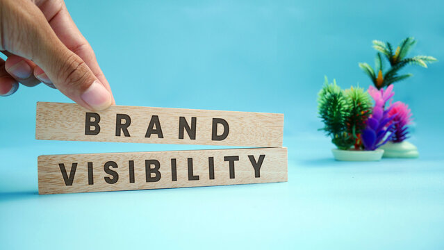 Brand visibility symbol on wooden blocks. Beautiful light blue background. Businessman hand Business and Brand visibility concept. Copy space.