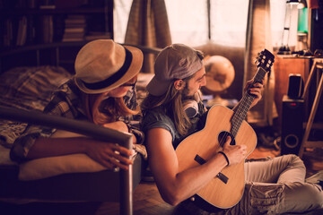 Young couple playing the guitar and singing in the bedroom together