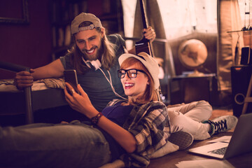 Young couple using a smart phone at home while playing the guitar and singing together