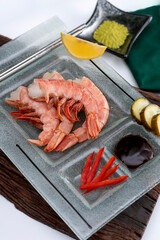 fresh prawns on a rectangular plate with wasabi dressings cheese pickles lemon and soy sauce