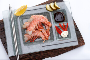 fresh prawns on a rectangular plate with wasabi dressings cheese pickles lemon and soy sauce