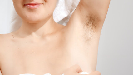 Closeup of young woman covered in white towel showing her long dark armpit hair. Concept of beautiful female, natural beauty, feminity and body hair.