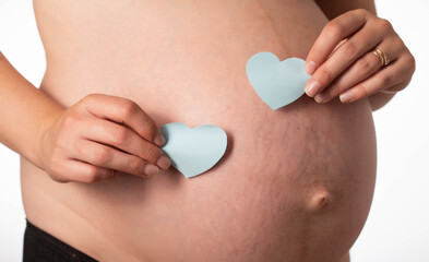 Two blue hearts on the background of the girl's pregnant belly. The concept of love for children...