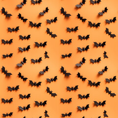 Halloween seamless pattern with black bats on orange background.