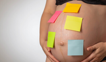 Blank multi-colored stickers are glued on the belly of a pregnant girl. In anticipation of the...