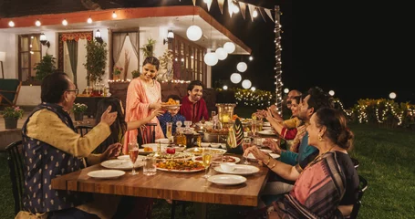 Crédence en verre imprimé Pleine lune Big Family Celebrating Diwali: Indian Family in Traditional Clothes Gathered Together on a Dinner Table in a Backyard Garden Full of Lights. Moment of Happiness on a Hindu Holiday