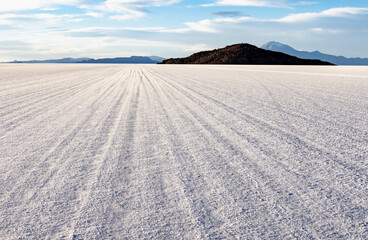 Driving on the biggest salt lake in the world, the Salar de Uyuni, with Isla Incahuasi in the distance - Bolivian Altiplano, South America