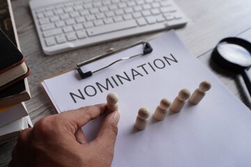 Hand pick wooden doll and text NOMINATION. Nominating a candidate for promotion. Select and...