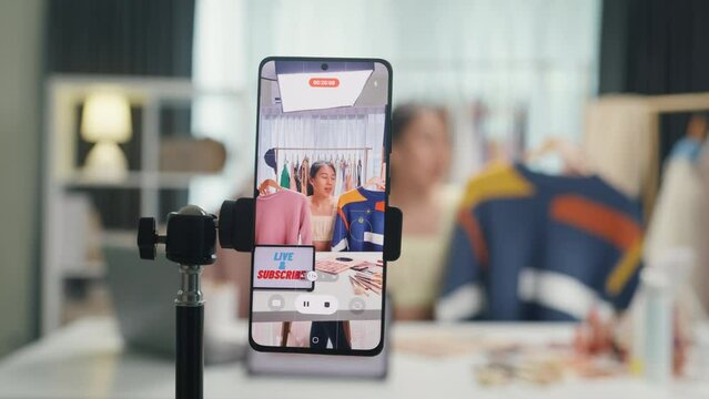 Close-up phone screen record Asia lady vlogger look phone camera review sweater new collection live selling online in IG story reel tiktok work at home studio. Business online media concept.