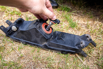 Replacing a burned out light bulb in a car headlight with an LED lamp. Close-up