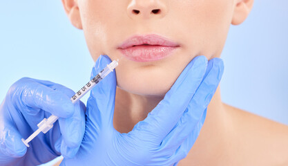 Injection, woman and lips with plastic surgeon for beauty with botox or hands in studio with blue...