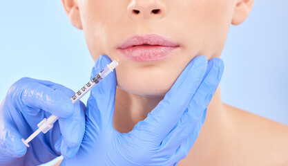 Injection, woman and lips with plastic surgeon for beauty with botox or hands in studio with blue background. Face, syringe and doctor for injecting mouth with collagen or filler and implants.
