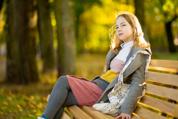Adorable young girl having fun on beautiful autumn day. Happy teenager portrait in autumn park.