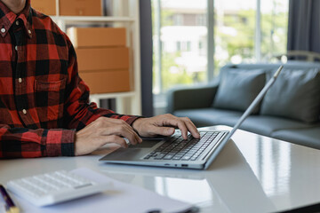 Asian businessman packing things and preparing to send them to customers with laptops on desks, small business owners, SMEs, shipping, postal delivery ideas Remote Picture