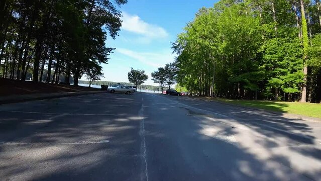 aerial FPV footage of a gorgeous summer landscape at Proctor Landing park with a lake a sandy beach, lush green trees and grass with blue sky and clouds at Lake Acworth in Acworth Georgia USA