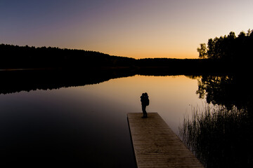 Silhouette of a mother with a child admiring beautiful waters of lake Gela on sunset.