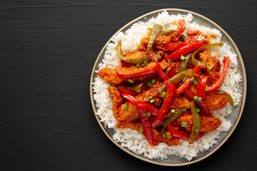 Homemade Simple Chili Chicken with White Rice on a Plate on a black background, top view. Flat lay, overhead, from above.