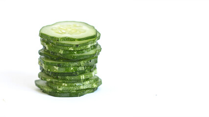 Cut cucumber slices are stacked on top of each other on a white background