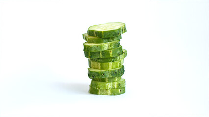 Cut cucumber slices are stacked on top of each other on a white background