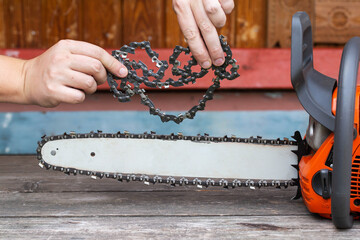 New chain for chainsaw. Setting up and replacing the chain on the chainsaw from the old to the new. Chain sharpening. Industry - obrazy, fototapety, plakaty