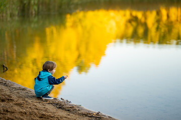 Adorable toddler boy having fun by the Gela lake on sunny fall day. Child exploring nature on...