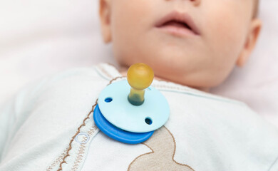 Little caucasian baby boy and pacifier. The habit of the sucking reflex in infants.