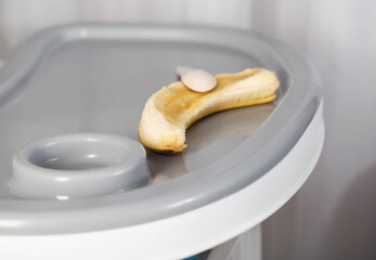 A banana with a spoon lies on a children's table. The concept of feeding babies with food. Copy space for text