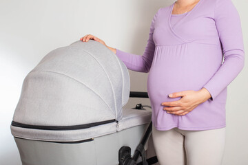 A pregnant girl with a big belly chooses a stroller for her unborn child. Buying a new baby...