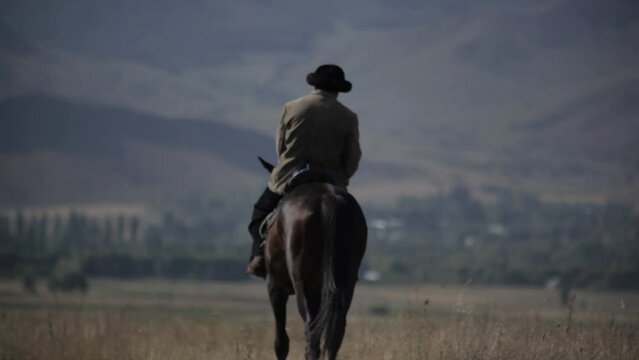 A man in a skullcap on a horse rides across the field