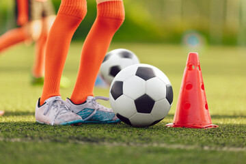 Legs of youth soccer player on training drill. Football summer training camp for children. Kids...