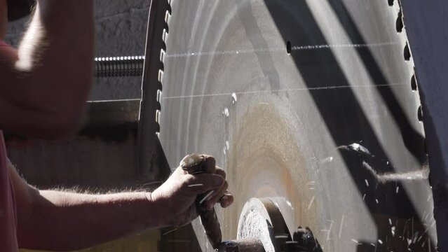 man adjusting the cutting disc, saw, for block or larger stone formats, hammering to disengage it