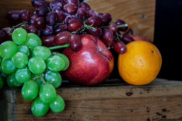 Bounty of fresh fruit on black background with wooden bench