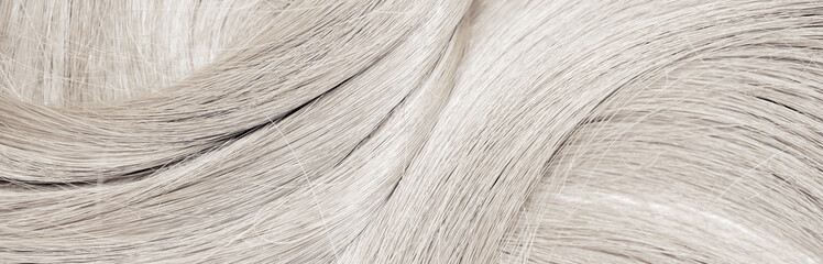 Blond hair close-up as a background. Women's long blonde hair. Beautifully styled wavy shiny curls....