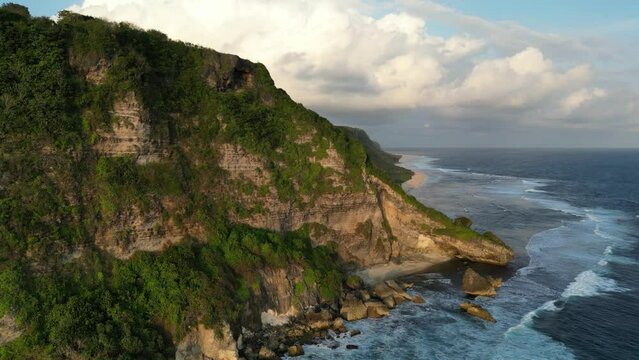 an aerial view of a cliff and ocean in Uluwatu, Bali