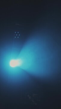 Scene illumination with a profiled blue beam of a profile spotlight in the smoke from a smoke machine from top to bottom Vertical format for the phone.